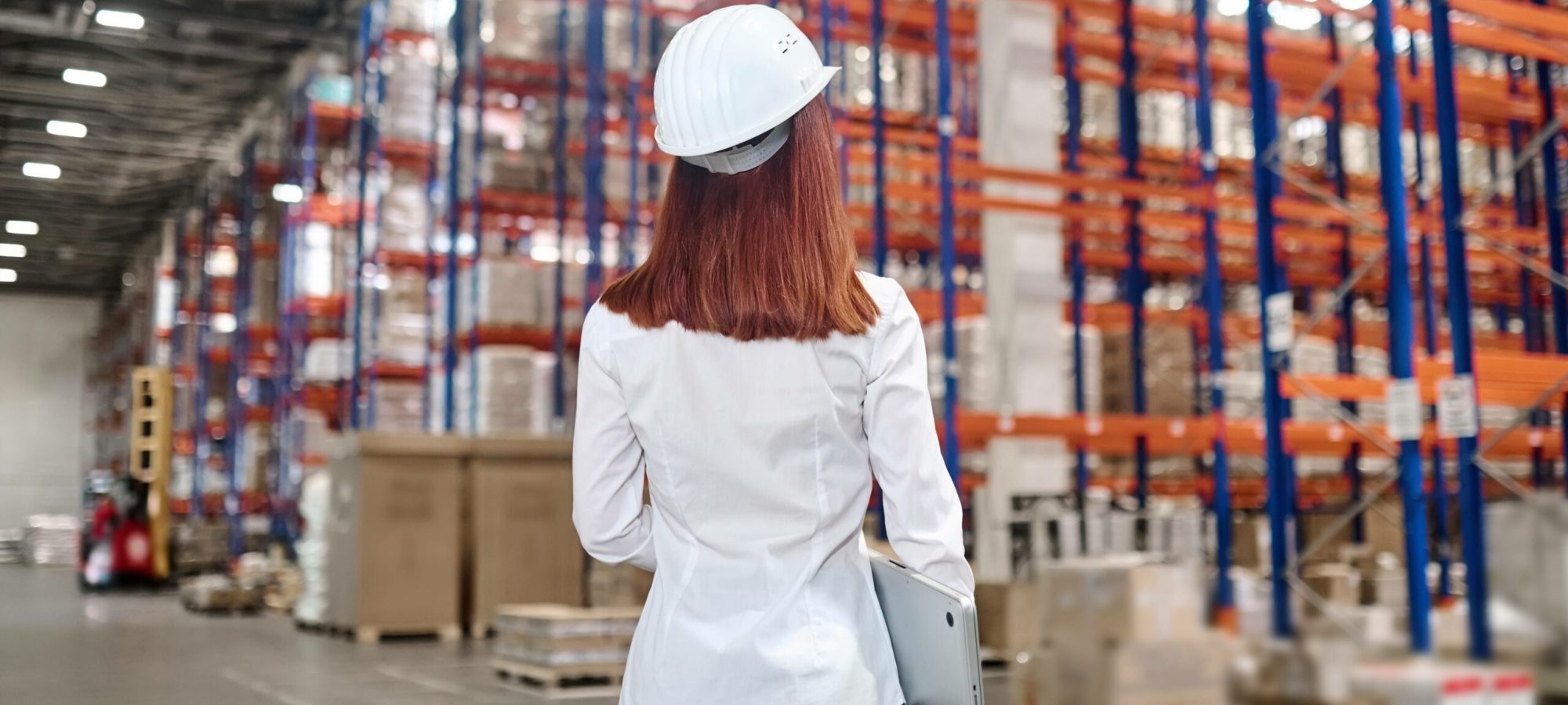 management-elegant-woman-white-safety-helmet-with-laptop-standing-warehouse-with-back-camera-looking-cargo-compartments